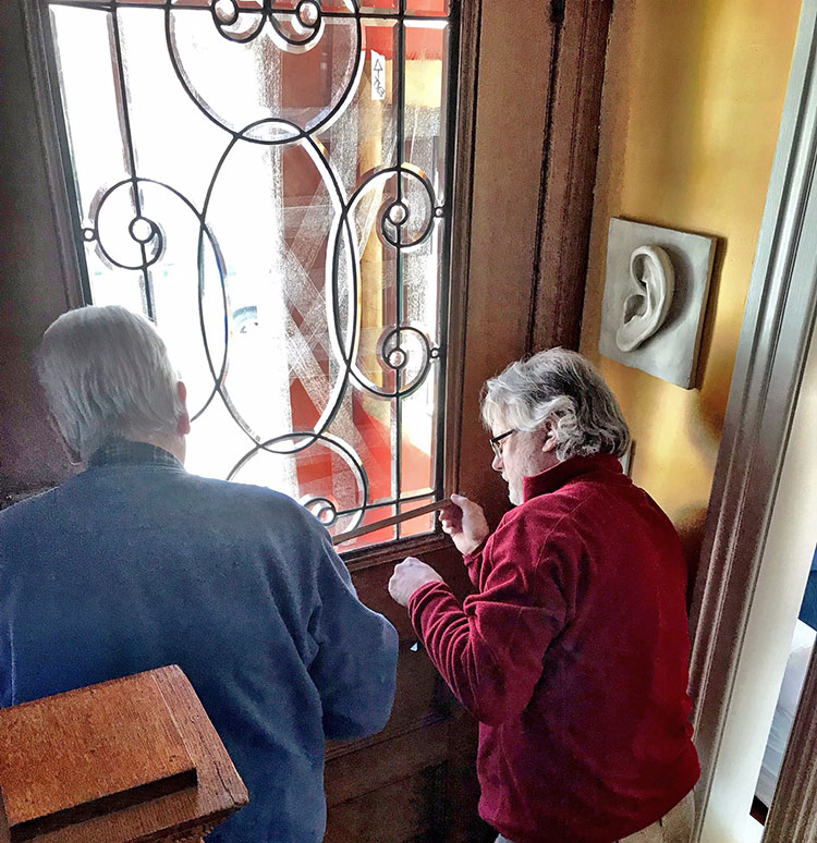 two people repairing details on a door